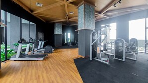 A gym with treadmills, weight machines, and a wooden floor.