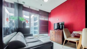 Ein modernes Wohnzimmer mit einer Couch, einem Fernseher, einem Holzschrank und einem Essbereich mit Tisch und Stühlen.
