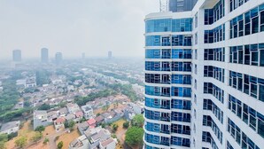 Ein Hochhaus mit mehreren Etagen und großen Fenstern, das auf ein Wohngebiet mit Häusern und Grünflächen blickt.
