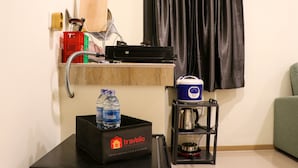 Una kitchenette con una cafetera, una botella de agua y una bolsa de viaje con la etiqueta 'Travelio'.