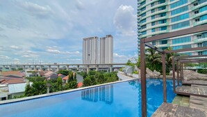 A swimming pool with a view of high-rise buildings and a bridge in the background. - Cozy 1Br Without Living Room Grand Kamala Lagoon Apartment (Bekasi)
