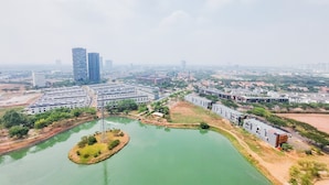 An aerial view of a modern urban area with high-rise buildings, a large open plaza, and a body of water with a small island. - Nice And Modern Studio At 38Th Floor Pacific Garden Apartment (Tangerang)