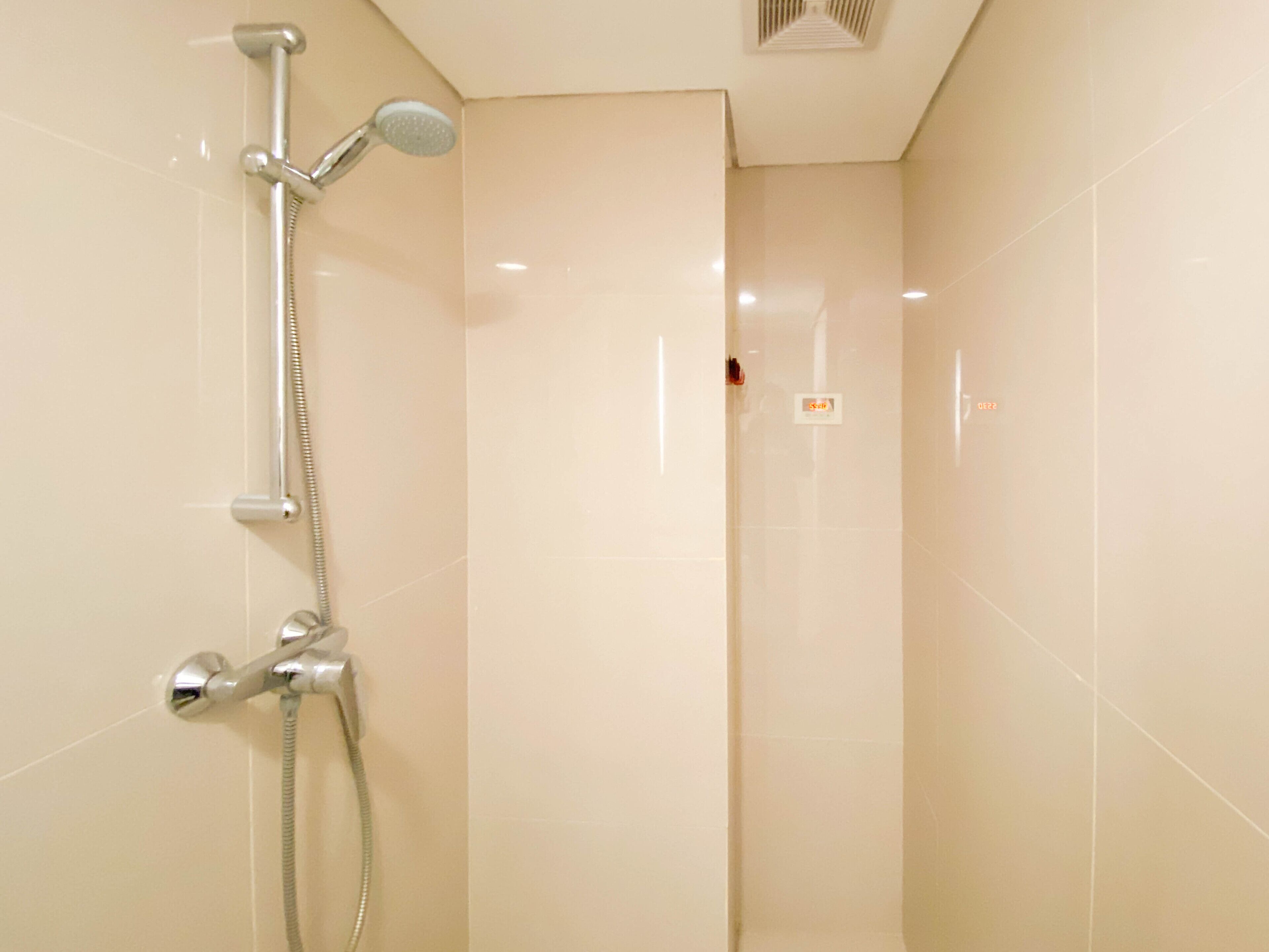 Een moderne badkamer met een douche, douchekop en een wandmengkraan.