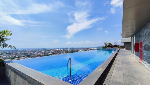 Une piscine à débordement offrant une vue imprenable sur le paysage urbain et l’océan en arrière-plan.