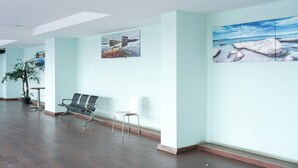 A spacious lobby with wooden flooring, a seating area with chairs, and two large landscape paintings on the walls. - Nice And Warm Studio At Belmont Residence Puri Apartment (Jakarta)
