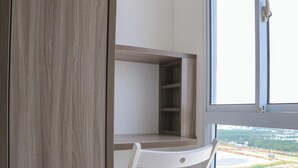 Ein Zimmer mit einem Holzkasten, einem weißen Stuhl und einem Fenster mit Blick auf eine Stadt.