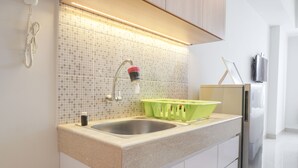 Una cocina moderna con un lavamanos doble, un escurreplatos verde y un refrigerador.