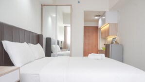 Una habitación de hotel con una cama grande, una mesita de noche, un armario y un espejo.