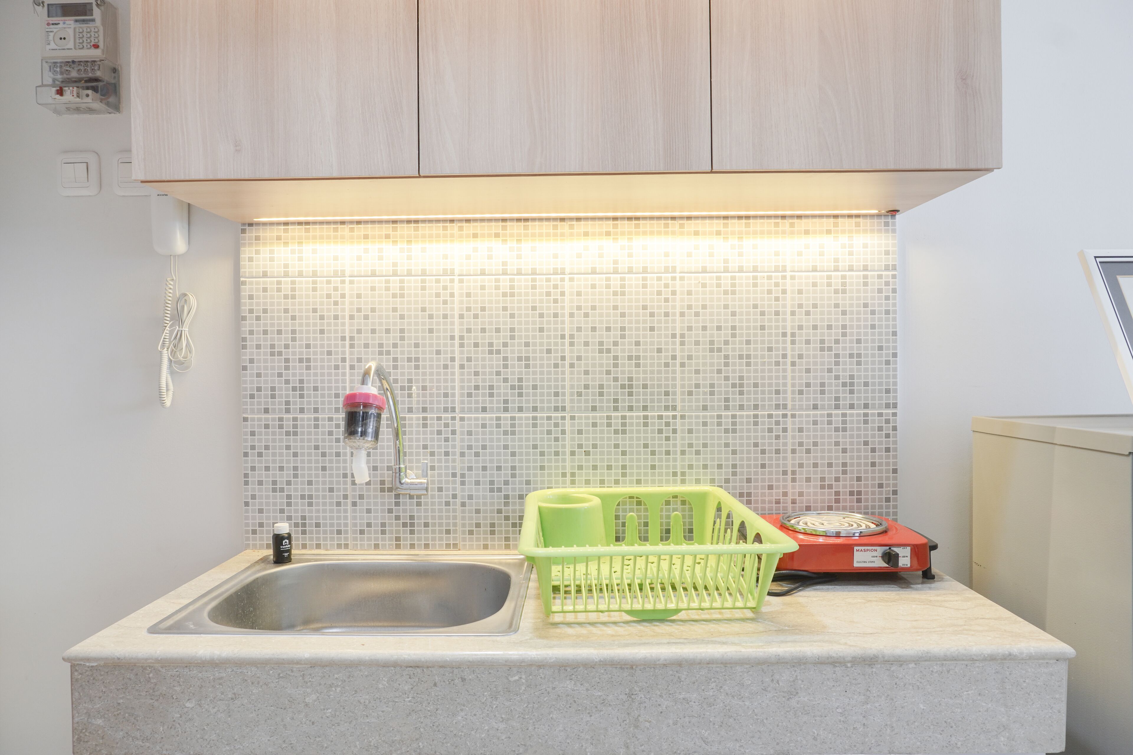 A kitchen with a sink, a green dish rack, a red stove, and a tiled backsplash.