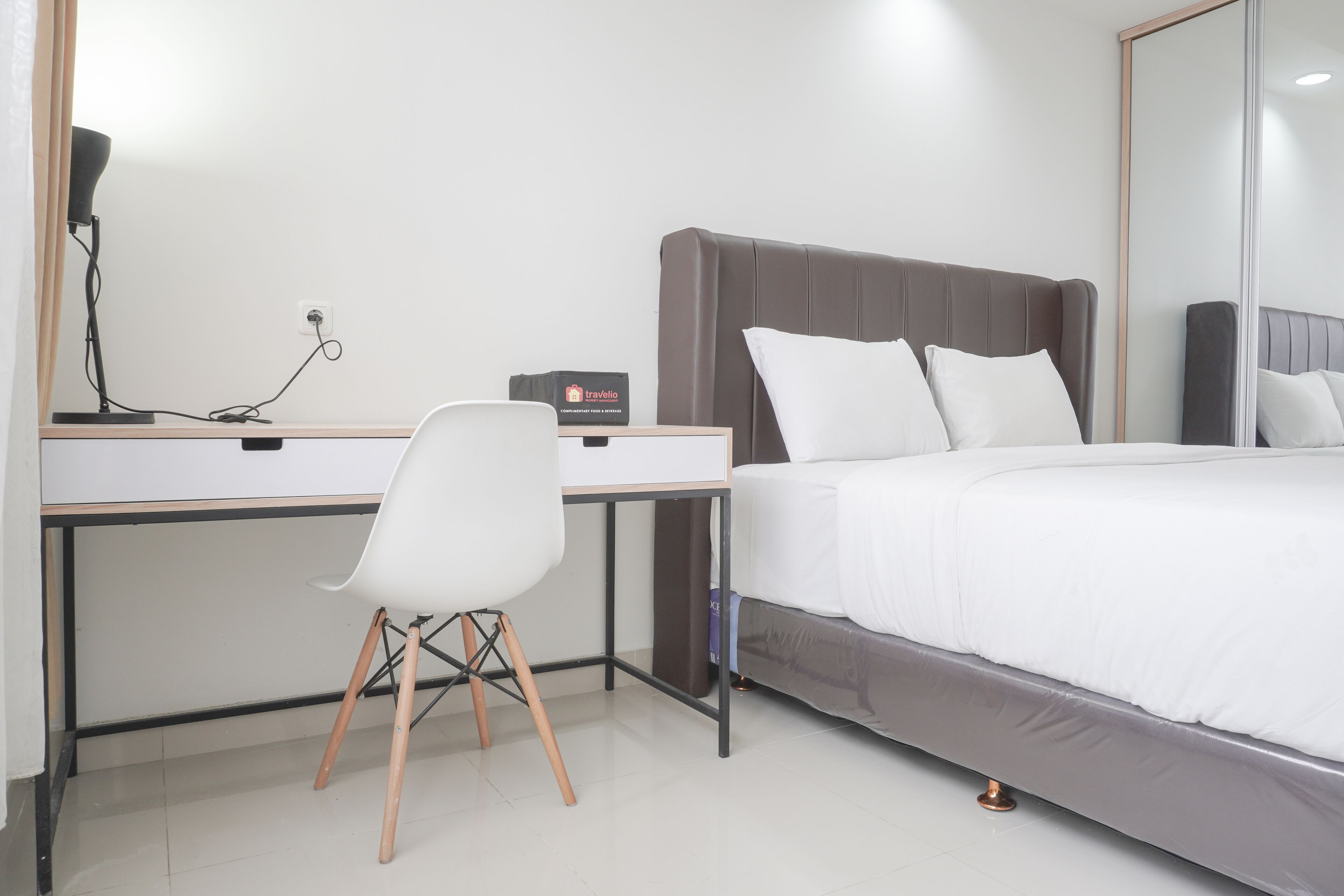 A modern hotel room with a bed, a desk, and a chair.