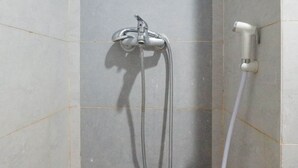 Eine Dusche mit einer Handbrause und einem fest installierten Duschkopf, beide an einer gefliesten Wand angebracht.