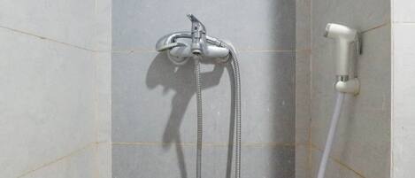 Una ducha con cabezal de ducha de mano y otro fijo, ambos instalados en una pared con azulejos.