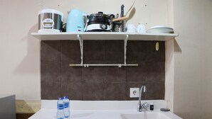 Une cuisine avec un plan de travail blanc, un évier et une étagère suspendue au-dessus.