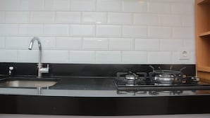 A kitchen with a black countertop, stainless steel sink, and a gas stove.