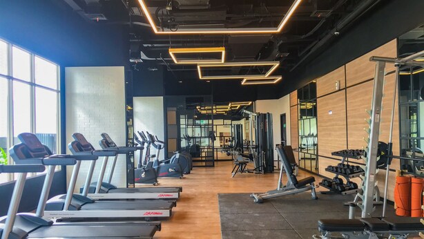 A gym with treadmills, weight machines, and a mirrored wall.