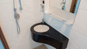 A bathroom with a black sink, white tiles, and a mirror. - Minimalist Studio At Sky House Bsd Apartment (Pagedangan)