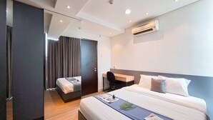 Ein modernes Hotelzimmer mit einem großen Bett, einem Schreibtisch und einem Spiegel.