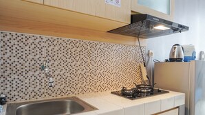 A kitchen with a tiled backsplash, stainless steel sink, and a gas stove. - Comfy And Minimalist Studio Dave Apartment Near Universitas Indonesia (Depok)