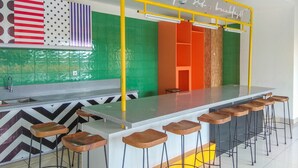 A modern kitchen with a bar area, green and orange walls, and a yellow bar counter. - Comfy And Minimalist Studio Dave Apartment Near Universitas Indonesia (Depok)