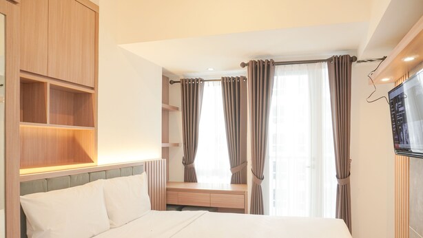Une chambre d’hôtel avec un lit, une armoire en bois, une télévision et une fenêtre avec des rideaux.