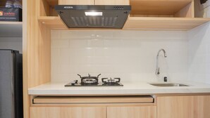 Une cuisine équipée d’une cuisinière à gaz, d’un évier, de meubles de rangement en bois et d’une boîte de la marque Travelio posée sur le plan de travail.