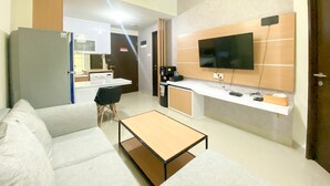 A modern living room with a sofa, coffee table, and a TV mounted on the wall. - Exclusive And Comfortable 1Br Apartment Mustika Golf Residence (Cikarang)
