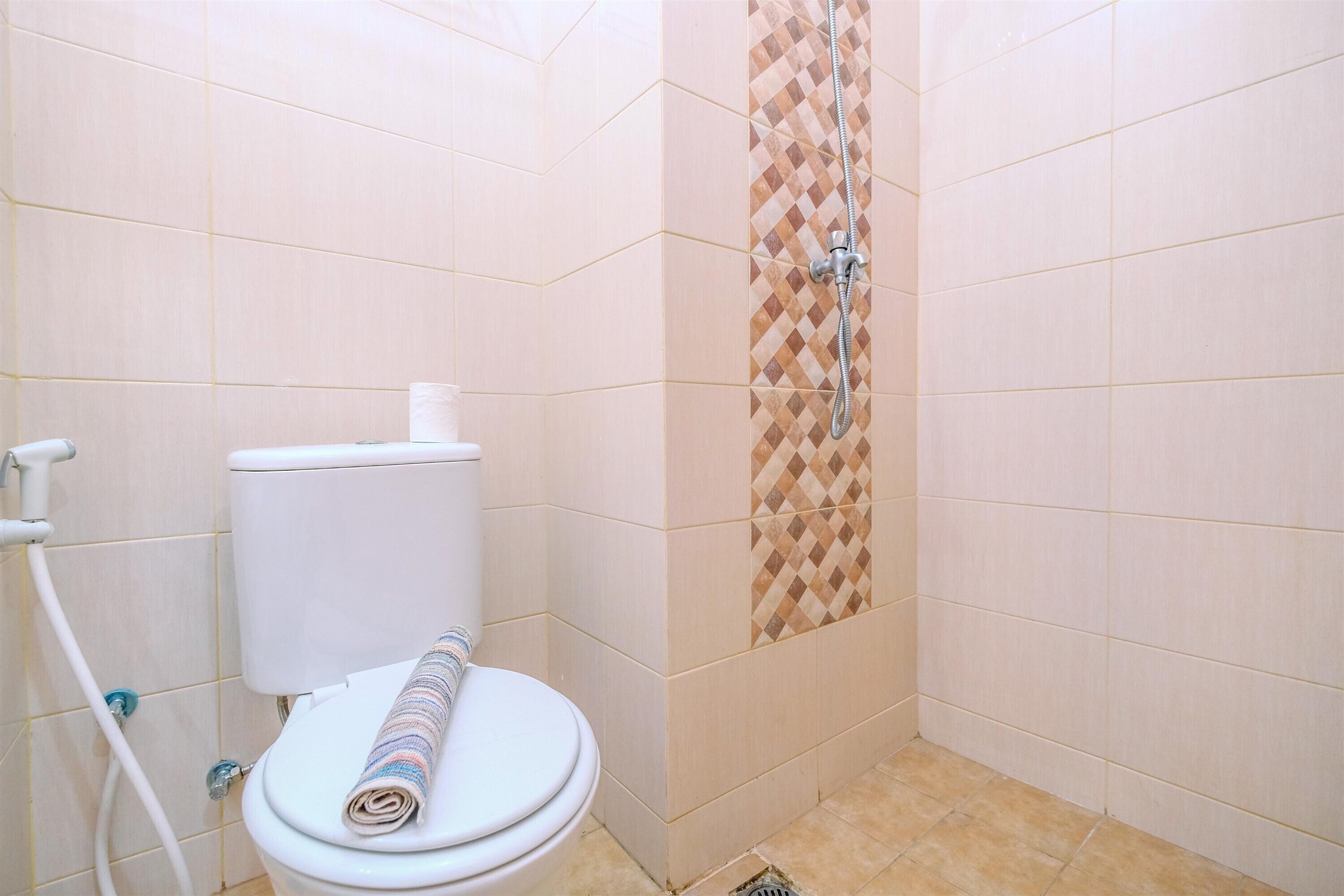 A bathroom with a toilet, a shower, and tiled walls.