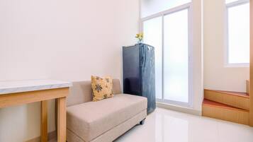 Un salón minimalista con sofá, una mesita, un armario y un ventanal que deja entrar luz natural.