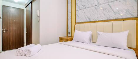 Una habitación de hotel con una cama grande, un armario de madera y un ventanal enmarcados en mármol.