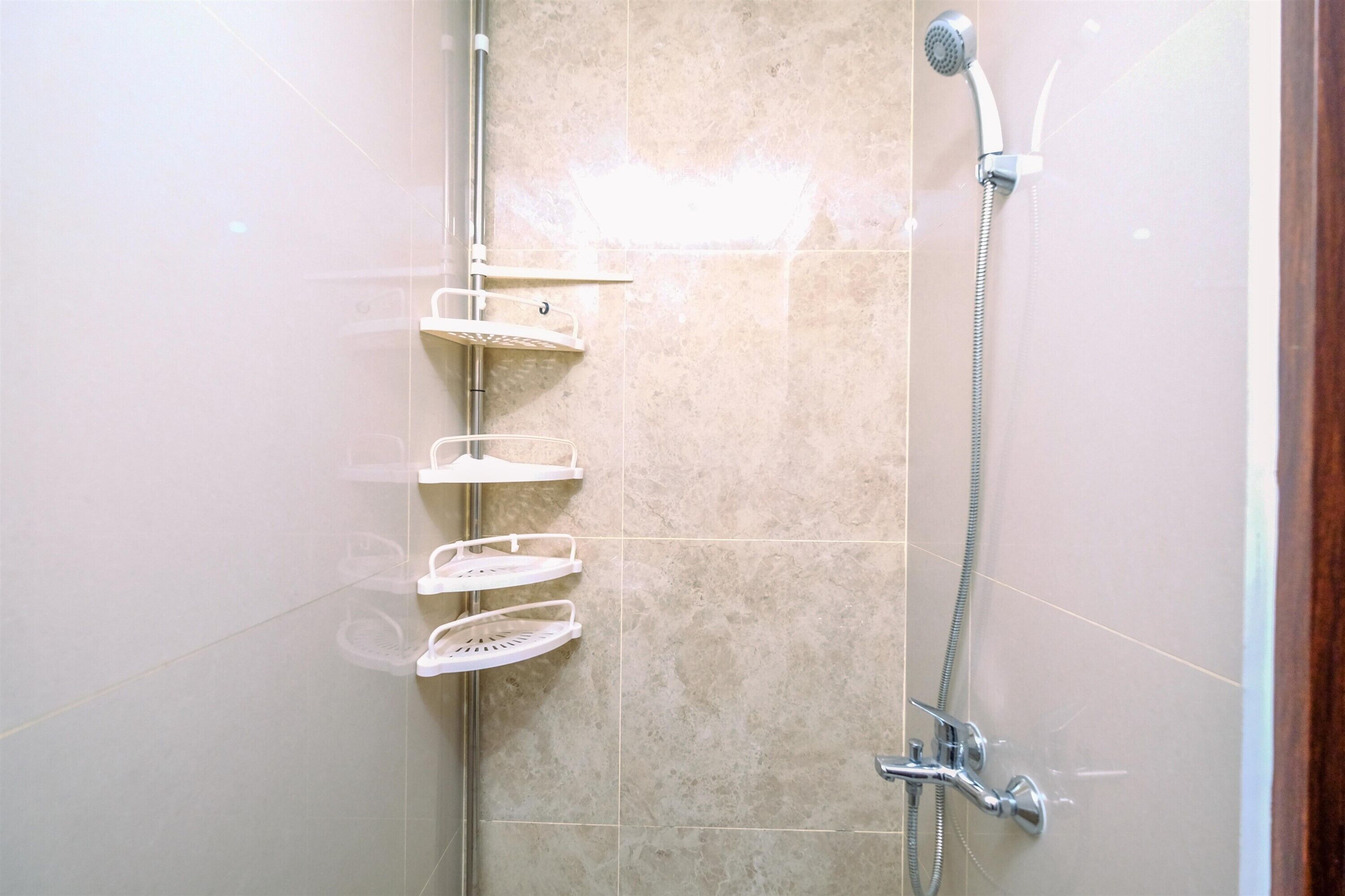 A shower with a handheld showerhead and a wall-mounted faucet, with two white towel racks.