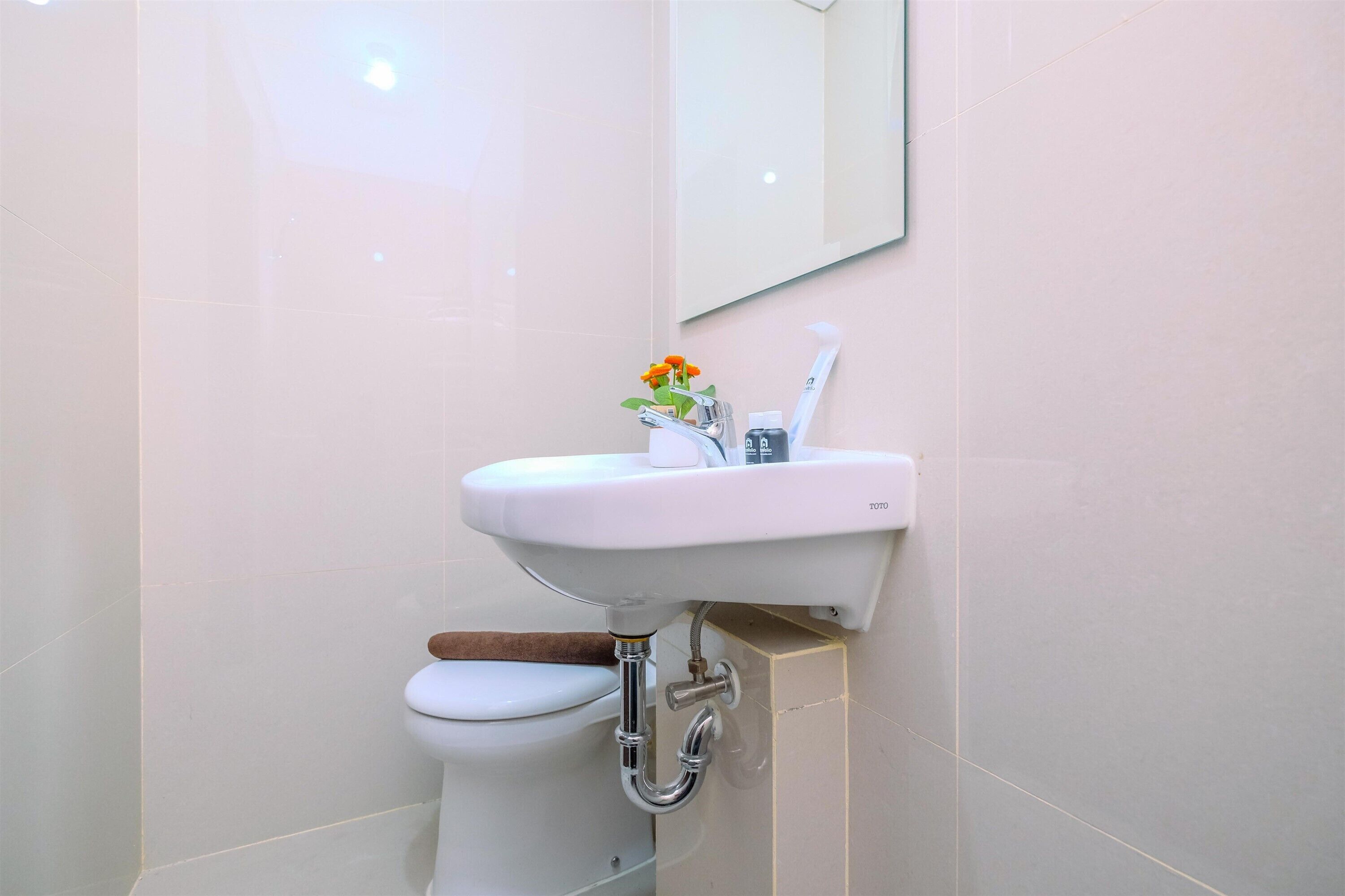 Un baño con lavamanos, espejo y retrete blancos.