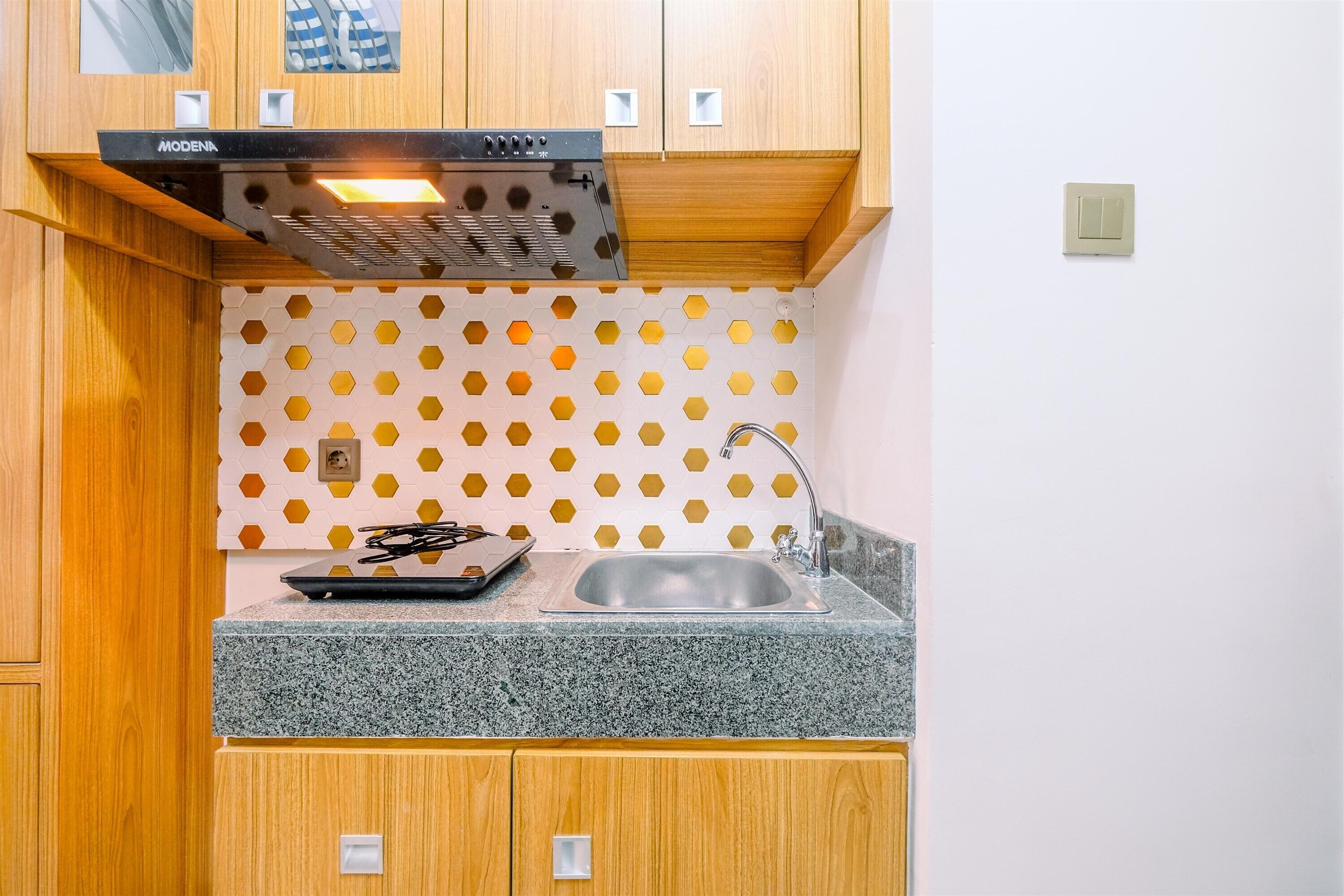 A kitchen with wooden cabinets, a stainless steel sink, and a hexagonal patterned backsplash.