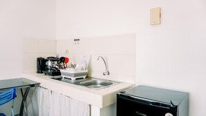 Una cocina compacta con un lavamanos, una cafetera y un refrigerador pequeño.