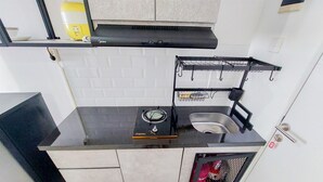 A compact kitchen with a gas stove, sink, and a small storage cabinet. - Luxury Studio At 19Th Floor Apartment Urbantown Serpong (South Tangerang)
