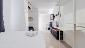 A hotel room with a bed, a desk, a chair, a TV, and a mirror. - Luxury Studio At 19Th Floor Apartment Urbantown Serpong (South Tangerang)
