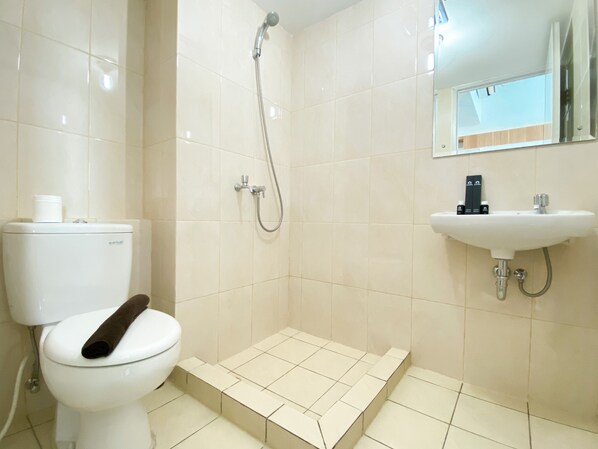A bathroom with a toilet, shower, and sink.