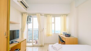 A hotel room with a bed, a TV, a desk, and a balcony.
