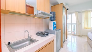 A compact kitchen with a sink, a gas stove, a water dispenser, and a refrigerator.