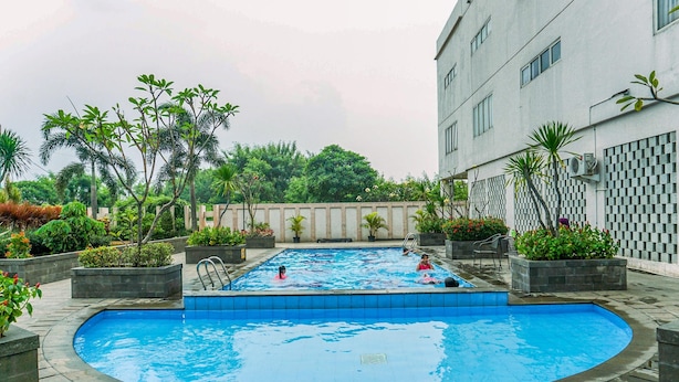 A swimming pool surrounded by planters and a building.