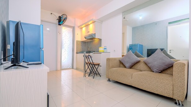 A modern living room with a sofa, a television, and a kitchen area with a stove and a chair.