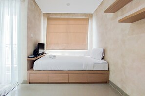 Un dormitorio con una cama, un televisor sobre un mueble bajo y una ventana con persianas.
