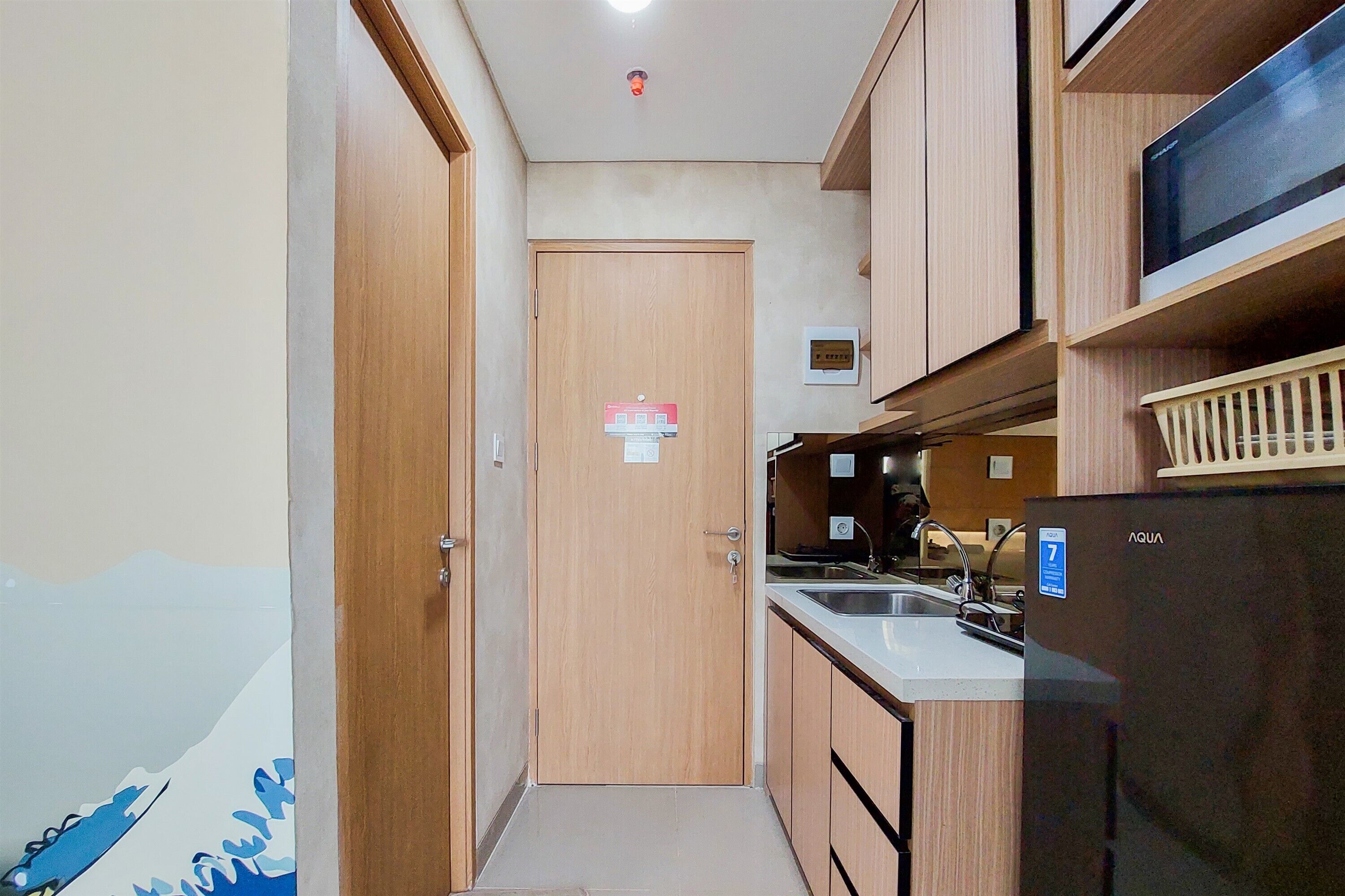 A compact kitchen with wooden cabinets, a refrigerator, and a microwave.