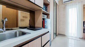 A modern kitchen with a stainless steel sink, wooden cabinets, and a built-in dishwasher. - Cozy Stay Studio Room Apartment At B Residence (Pagedangan)