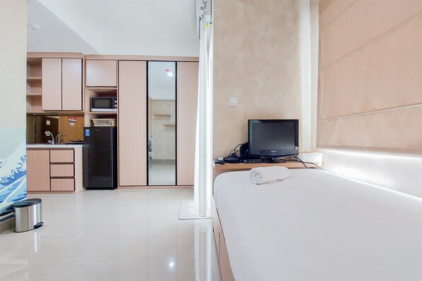Una habitación de hotel moderna con cama, televisión, microondas y refrigerador.