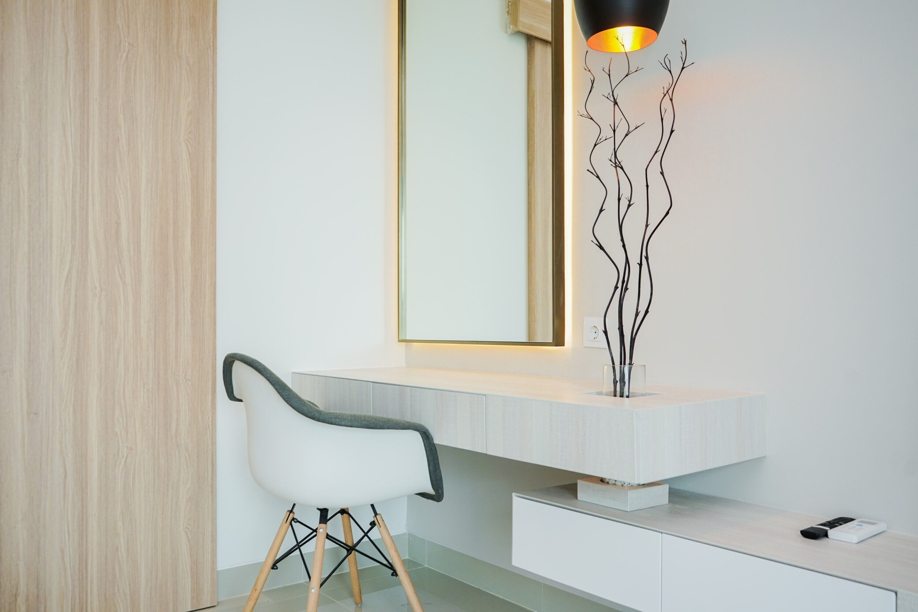 Une salle de bain moderne avec un meuble-lavabo blanc, une chaise et une sculpture décorative en forme de branche.