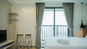 A modern hotel room with a large bed, two stools, a TV, and a balcony with curtains. - Cozy And Homey Studio At Bintaro Embarcadero Apartment (South Tangerang)