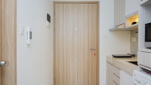 A compact kitchen with a wooden door, a microwave, and a washing machine. - Cozy And Homey Studio At Bintaro Embarcadero Apartment (South Tangerang)