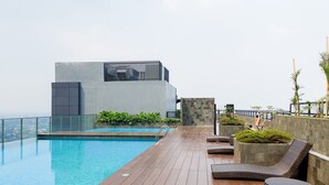 Zona de piscina en la azotea con piscina moderna, sillas de descanso y vistas de la ciudad.