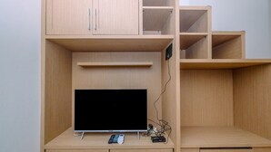 Un mueble de madera con un televisor de pantalla plana, un control remoto y una regleta para enchufes.