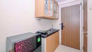 Una cocina compacta con armarios de madera, encimera negra y lavavajillas integrado.